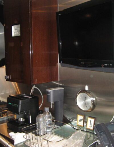 Modern kitchen with stainless steel backsplash, wooden cabinets, and mounted television.