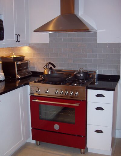 Modern kitchen with stainless steel stove and red accents.