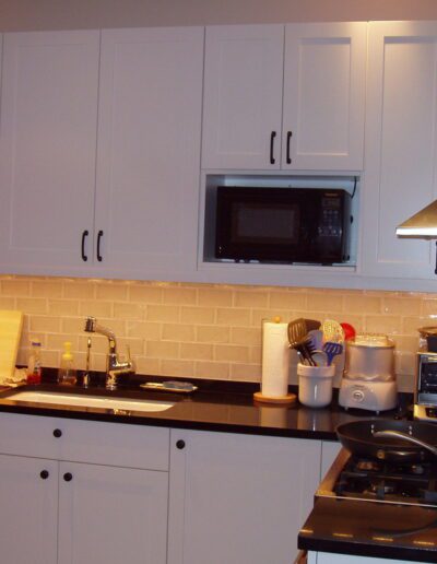 Modern kitchen with white cabinetry and stainless steel appliances.