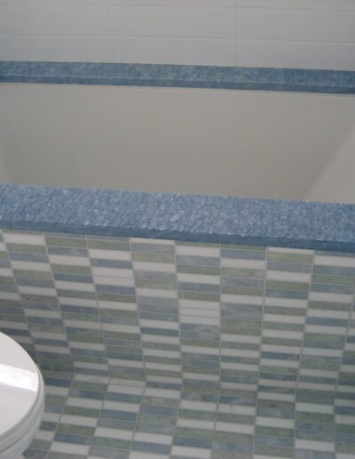 Built-in bathtub with blue surround and tiled bathroom wall.