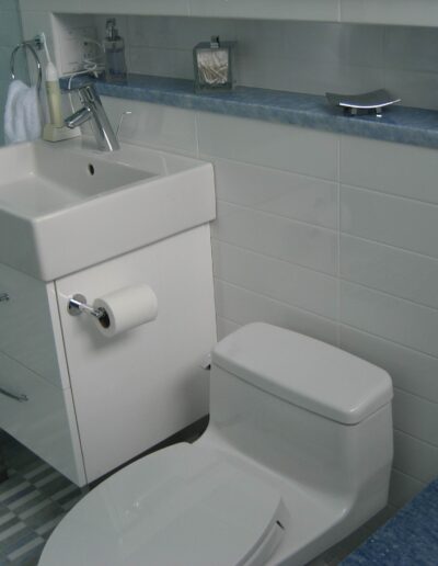 A modern bathroom with a white toilet and pedestal sink, featuring blue and white tiles.