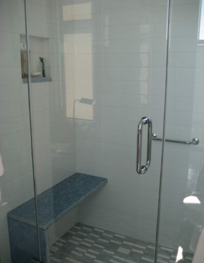 A modern bathroom with a glass shower enclosure and a built-in bench.