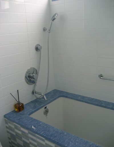 A modern bathroom corner with a built-in bathtub and a wall-mounted shower head.