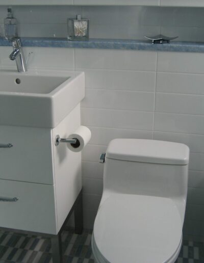 A clean and simple bathroom interior featuring a white pedestal sink, toilet, and tiled flooring.