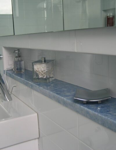 Modern bathroom interior with white tiles, a bathtub, and various toiletries on a blue countertop.