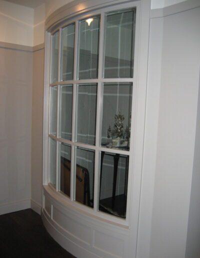 White framed bay window in a room, showing partial interior view through the glass panes.