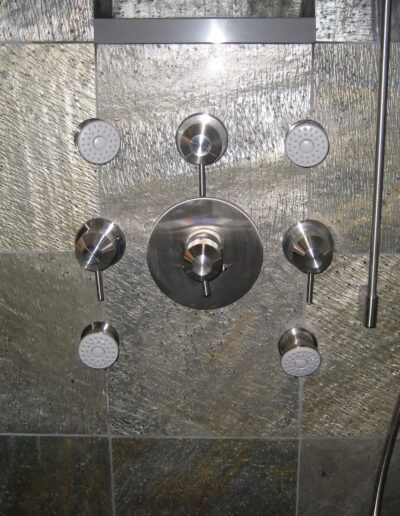 A modern shower system with multiple nozzles mounted on a tiled wall.