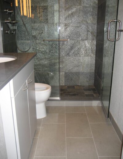 Modern bathroom interior with a glass shower enclosure, tiled walls, and a white toilet.