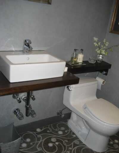 Modern bathroom with a rectangular vessel sink and a toilet, featuring a wooden countertop and decorative elements.