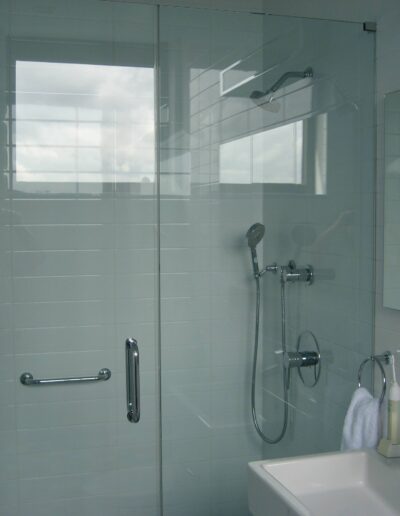 Modern bathroom interior with a glass shower stall, sink, and mirror.