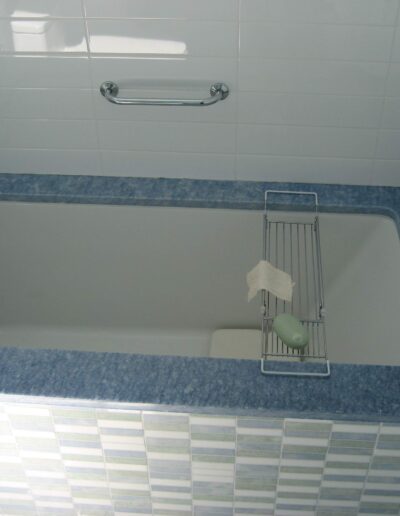 Modern bathtub with blue and white tile surround and various bath accessories.