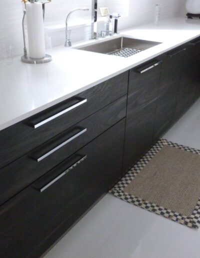 Modern kitchen with dark cabinets, stainless steel sink, and a patterned floor mat.