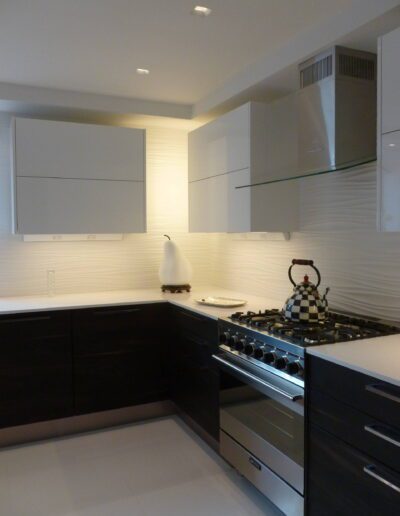 A modern kitchen with white walls, dark cabinets, and stainless steel appliances.