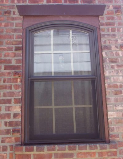 A window with a dark frame set in a red brick wall.