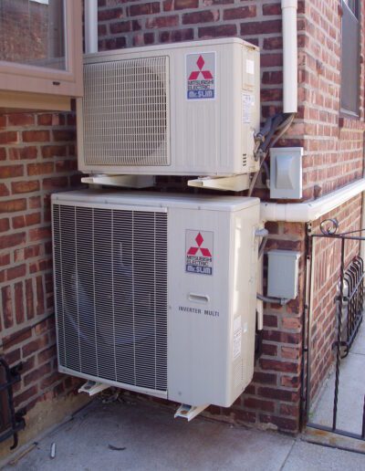 Outdoor unit of a mitsubishi split-type air conditioner mounted on a brick wall.