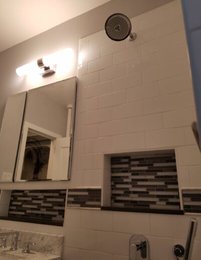 Modern bathroom with a glass shower, tiled walls, and a mirrored medicine cabinet.