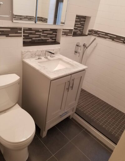 Modern bathroom interior with white fixtures and gray tiling.