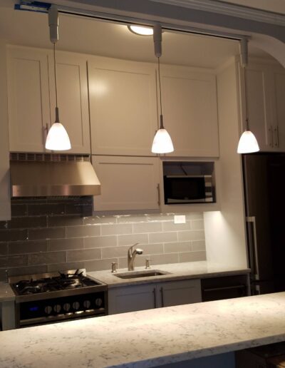 Modern kitchen with stainless steel appliances, white cabinetry, and pendant lighting over the island.