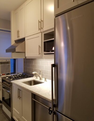 A modern kitchen featuring stainless steel appliances, white cabinetry, and a subway tile backsplash.