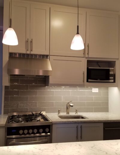 Modern kitchen interior with stainless steel appliances and pendant lighting.