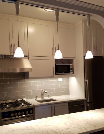 Modern kitchen with stainless steel appliances, white cabinetry, and pendant lighting.