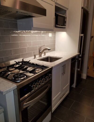 Modern kitchen with stainless steel appliances and dark floor tiles.