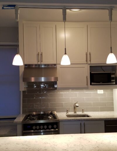 Modern kitchen with stainless steel appliances, white cabinetry, and pendant lighting.