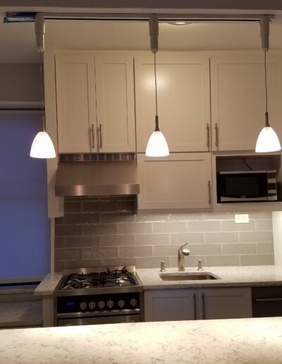 Modern kitchen with white cabinets, stainless steel appliances, and pendant lighting.