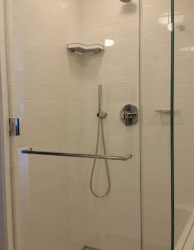 A modern bathroom with a glass-door shower and white tiles.