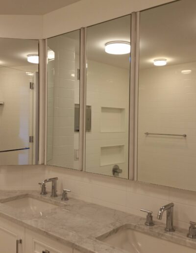 A modern bathroom with double sinks, marble countertops, and a large mirror with built-in lighting.