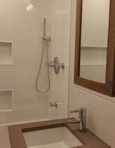 Modern bathroom interior with a glass shower enclosure and a wall-mounted sink.