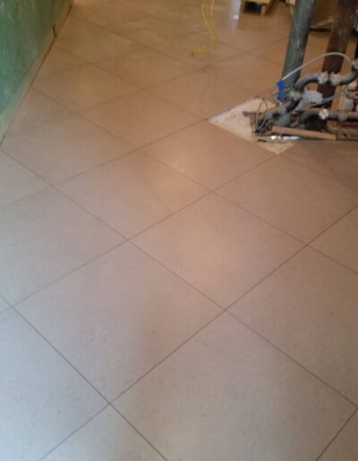 Newly laid floor tiles in a room under renovation with construction materials visible.